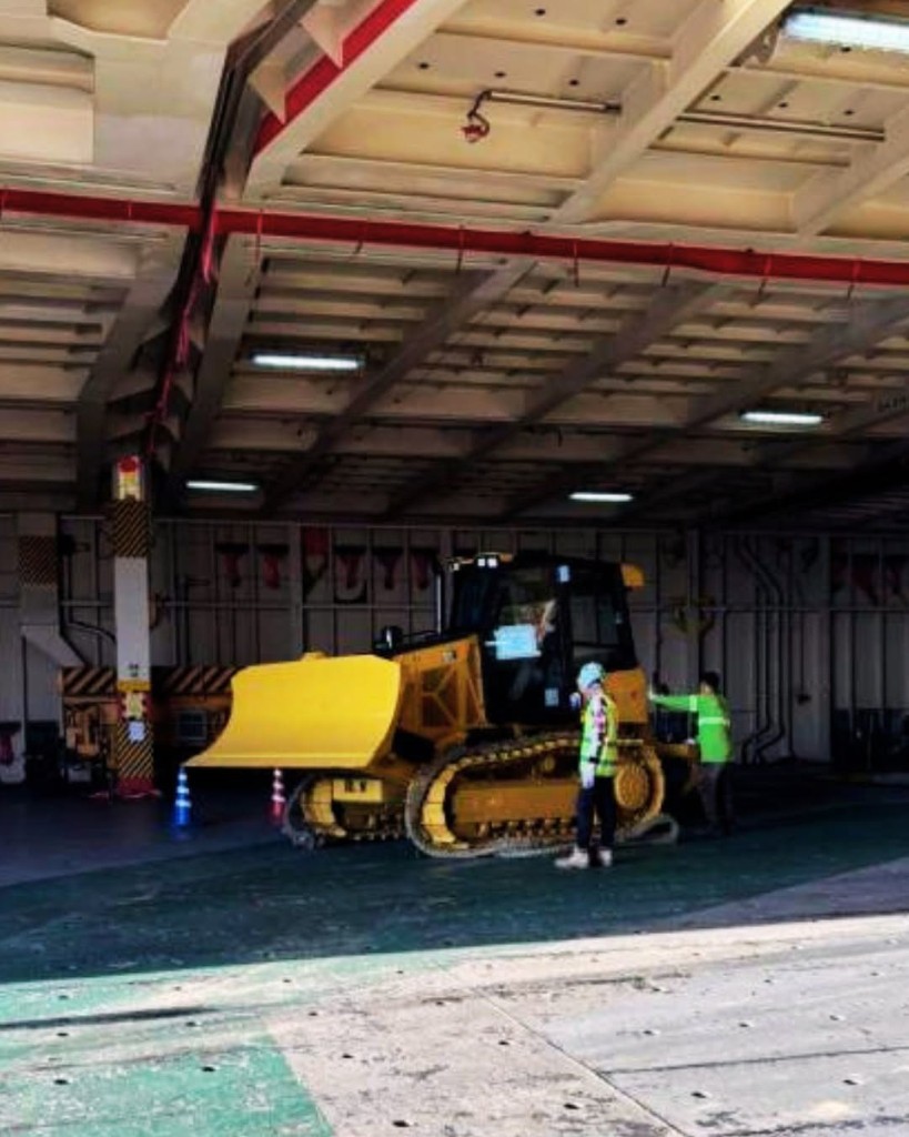 CAT dozer inside RORO cargo hold with workers securing the unit