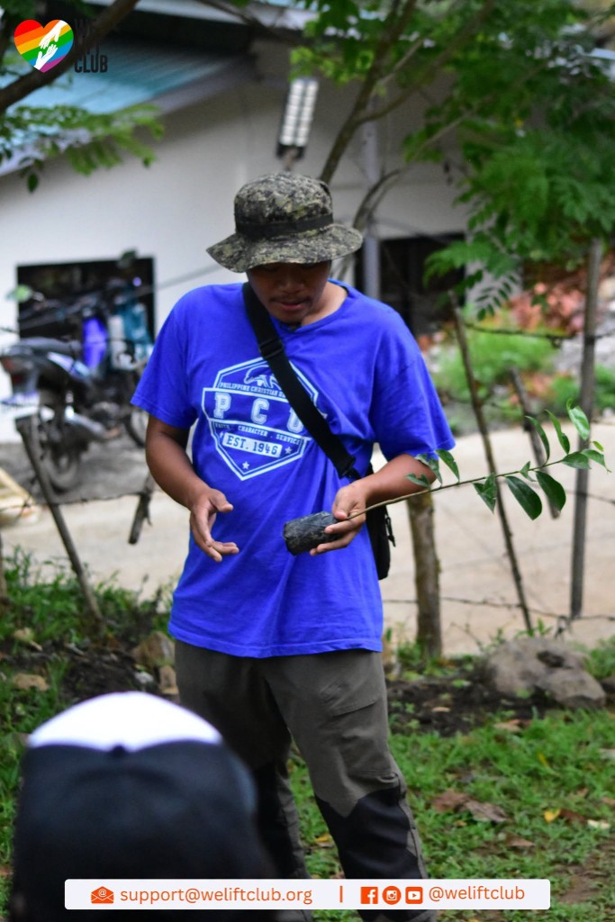 Community partner holding a tree sapling at the planting site