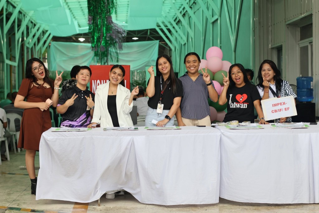 Nonpareil staff at the 35th Anniversary Thanksgiving Mass registration table posing with peace signs and festive decorations