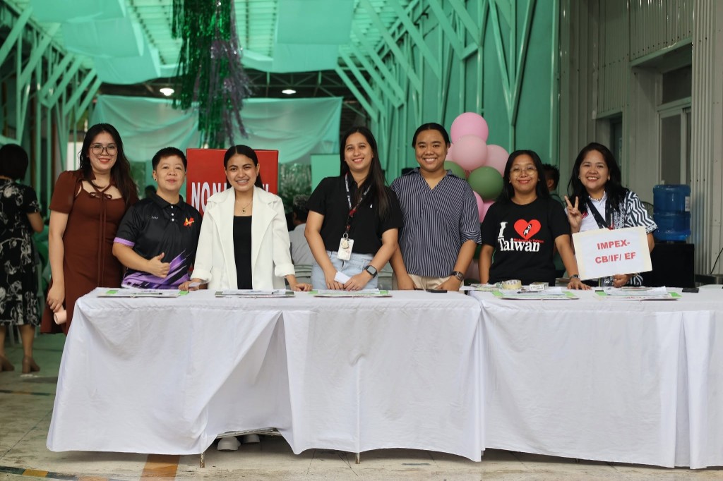 Seven women at the Nonpareil 35th Anniversary Thanksgiving Mass registration table with balloons and event decorations