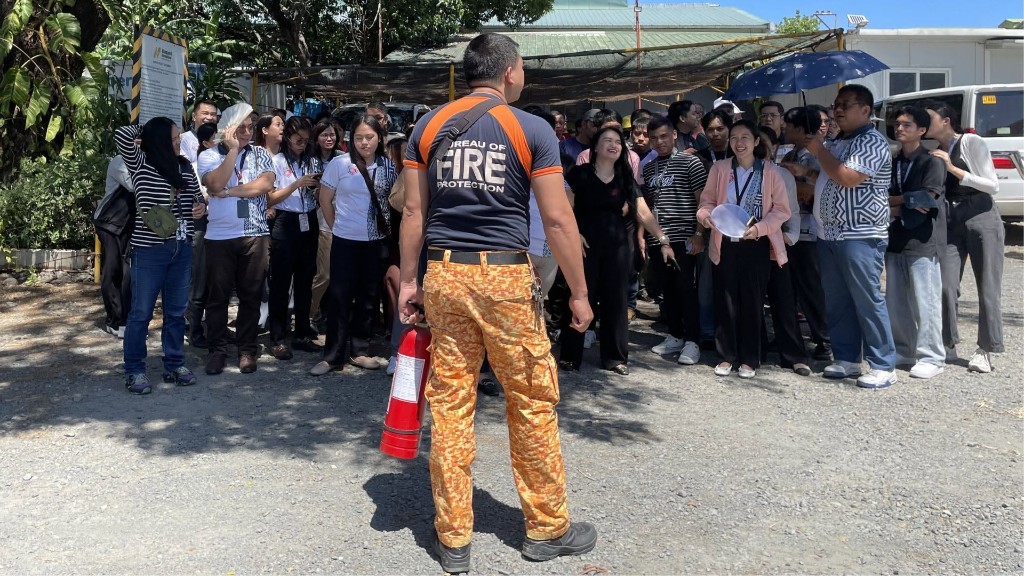 BFP officer demonstrating fire extinguisher use to group of Nonpareil employees outdoors